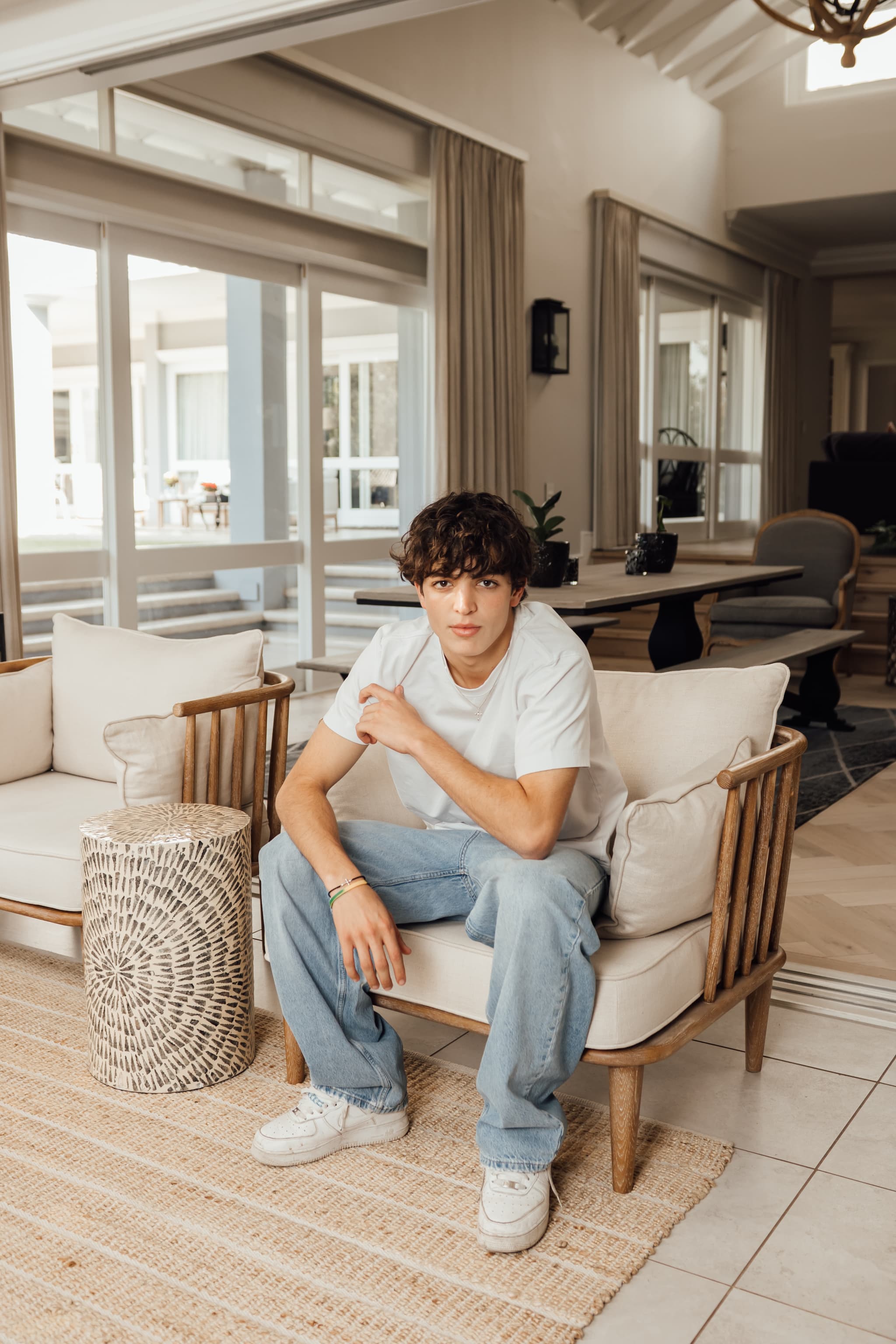 Antimo on a cream armchair indoors, in a white tee and light wash jeans