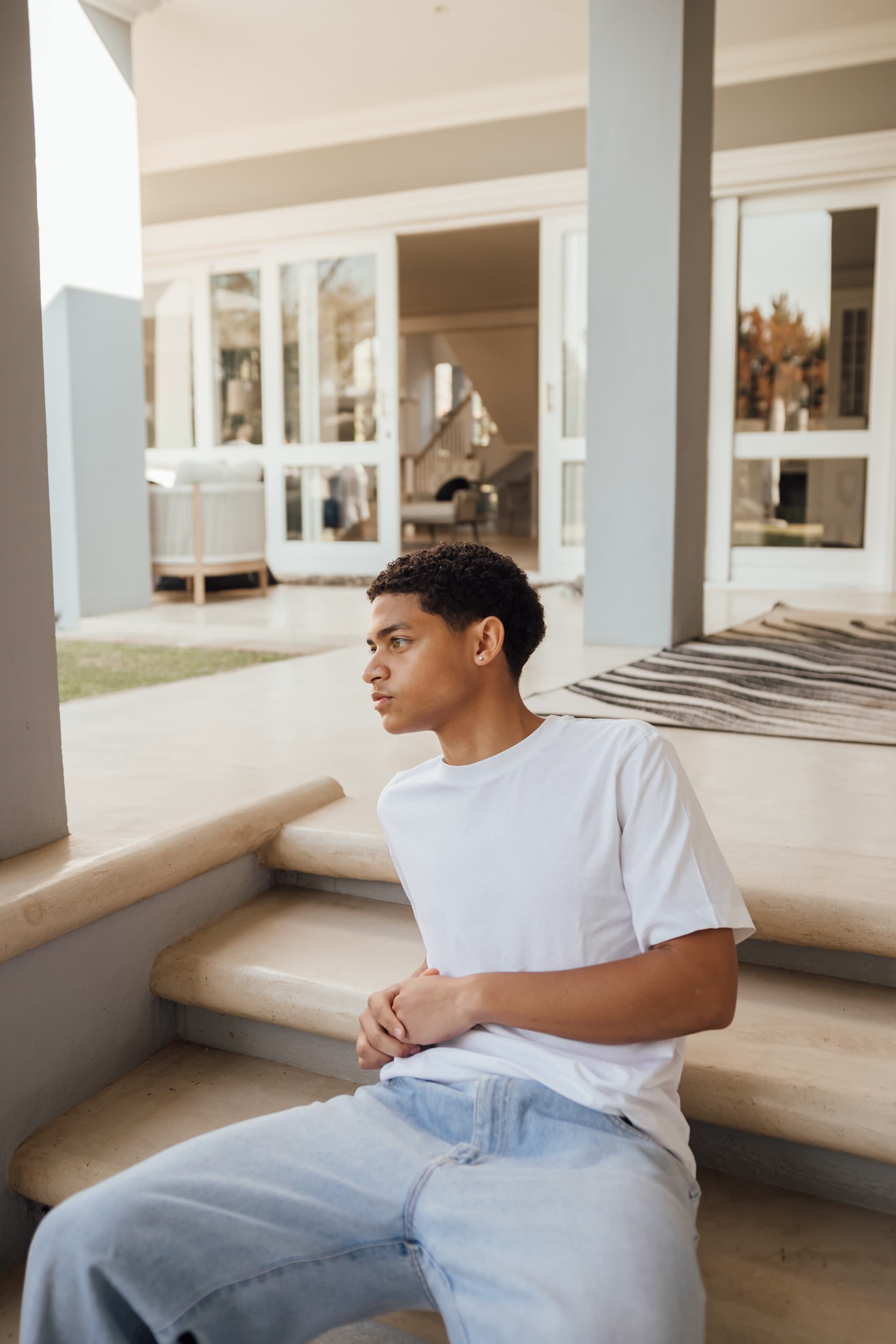 Ethan seated on stone steps outside, looking away