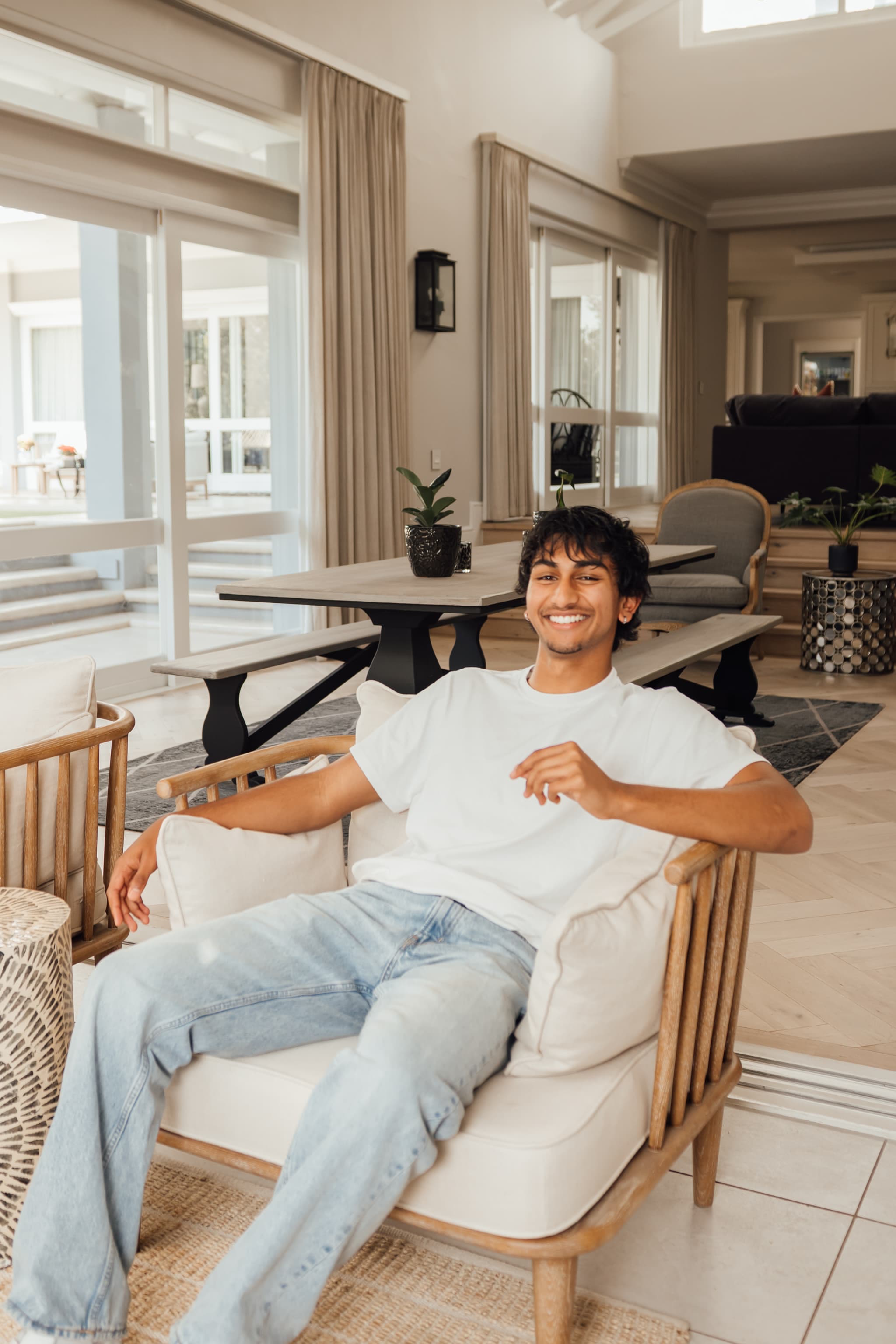 Kaedon smiling in a cane armchair indoors